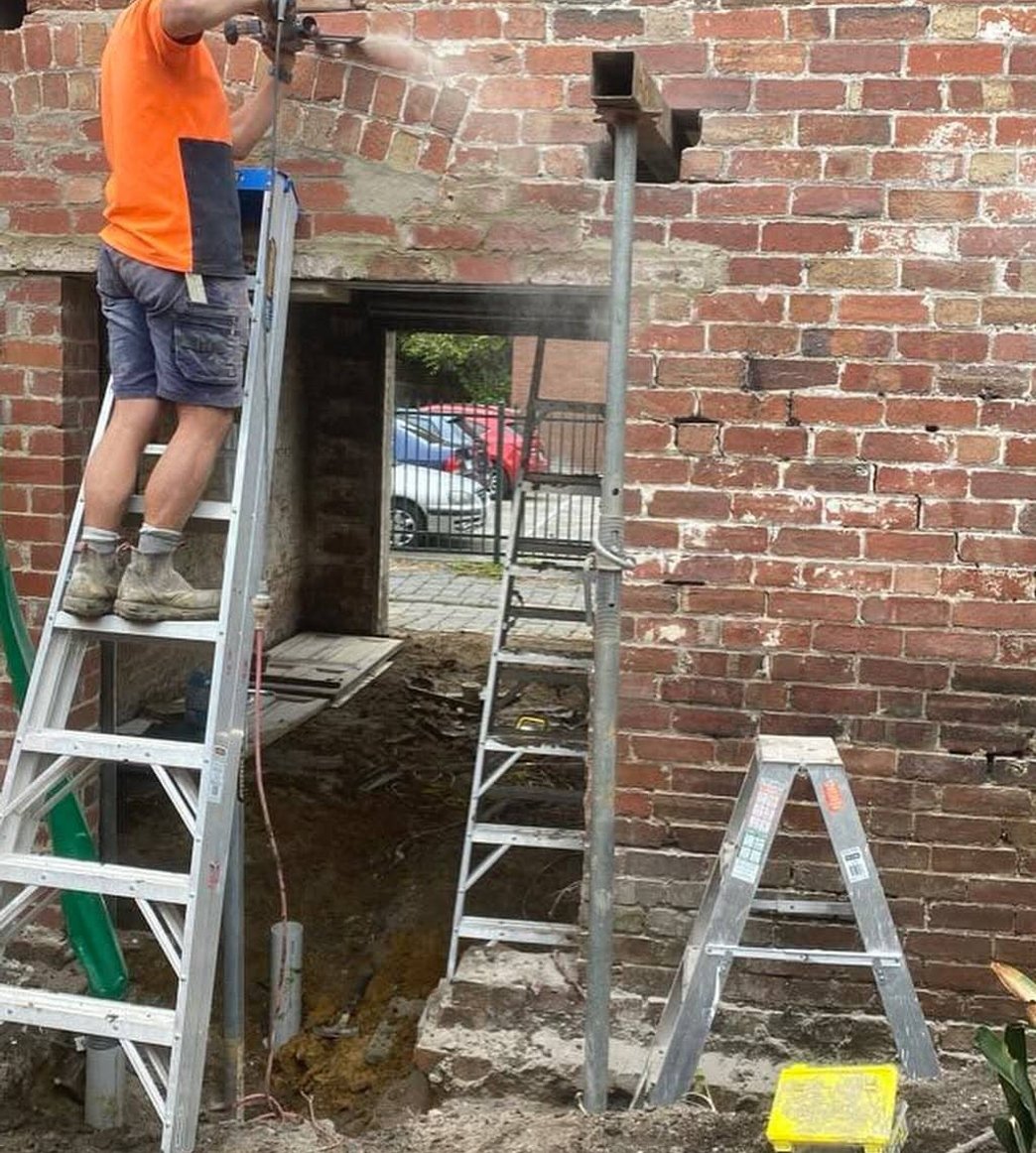 Bricklayer cutting a structural opening in a period red brick wall