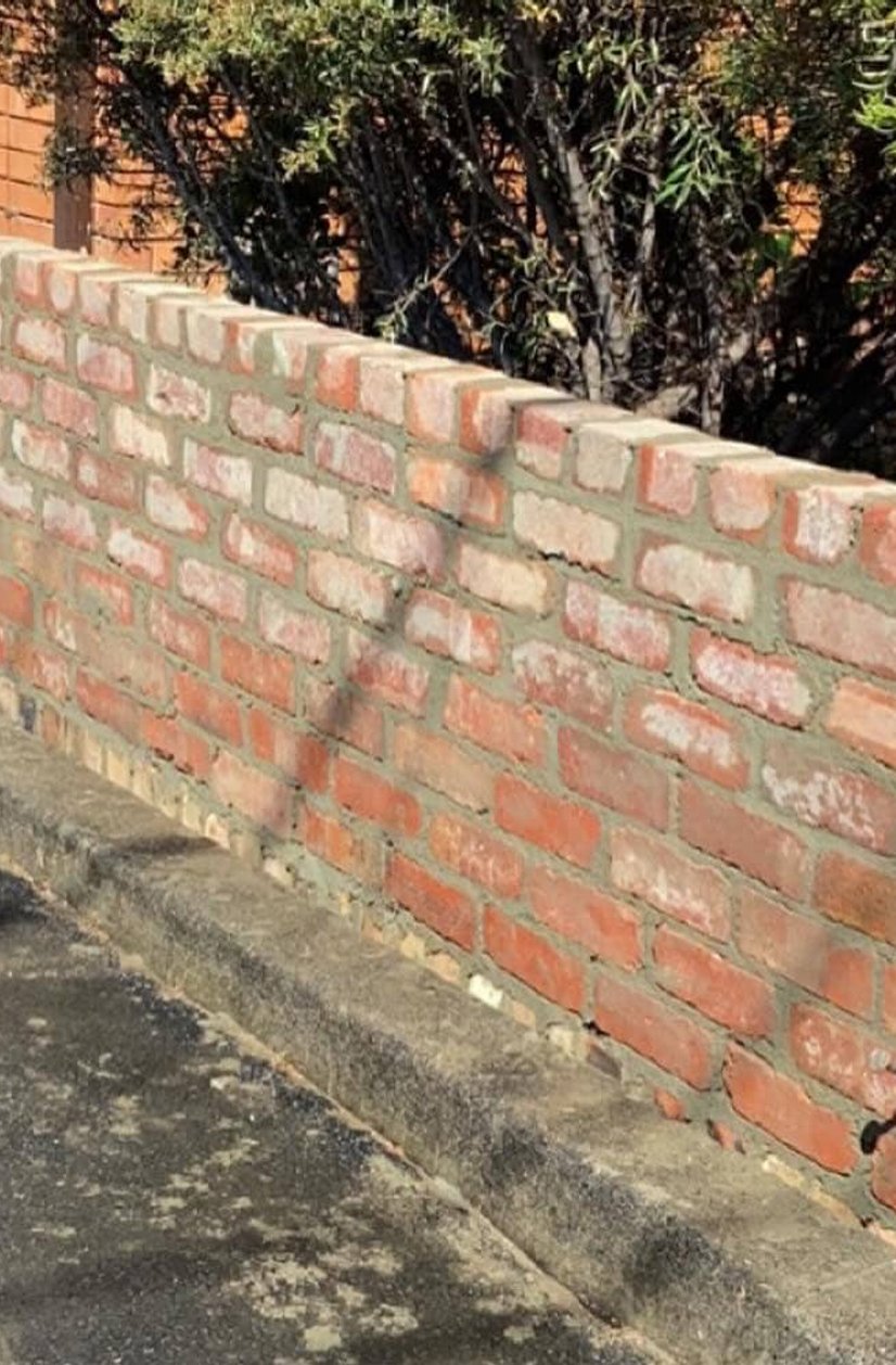 Low rustic red brick garden wall with flat brick capping